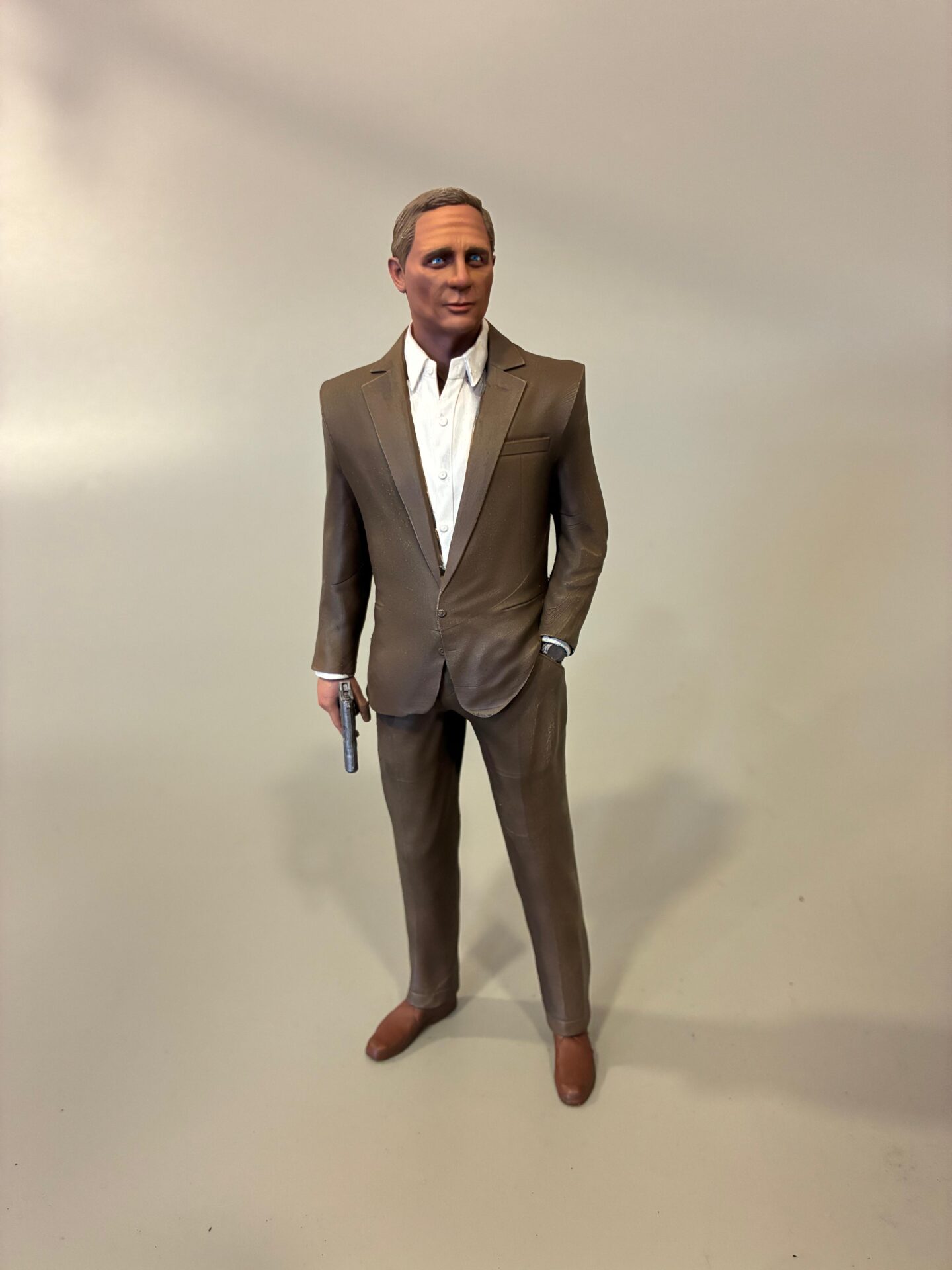 3D štampana figura muškarca u elegantnom odelu sa pištoljem, izrađena za kolekcionarsku namenu